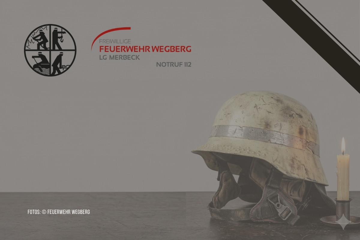 Trauerbild der Freiwilligen Feuerwehr Wegberg, LE Merbeck: Ein alter Feuerwehrhelm mit Atemschutzmaske liegt auf einer dunklen Fläche neben einer brennenden Kerze. In der oberen rechten Ecke befindet sich ein schwarzes Trauerband.